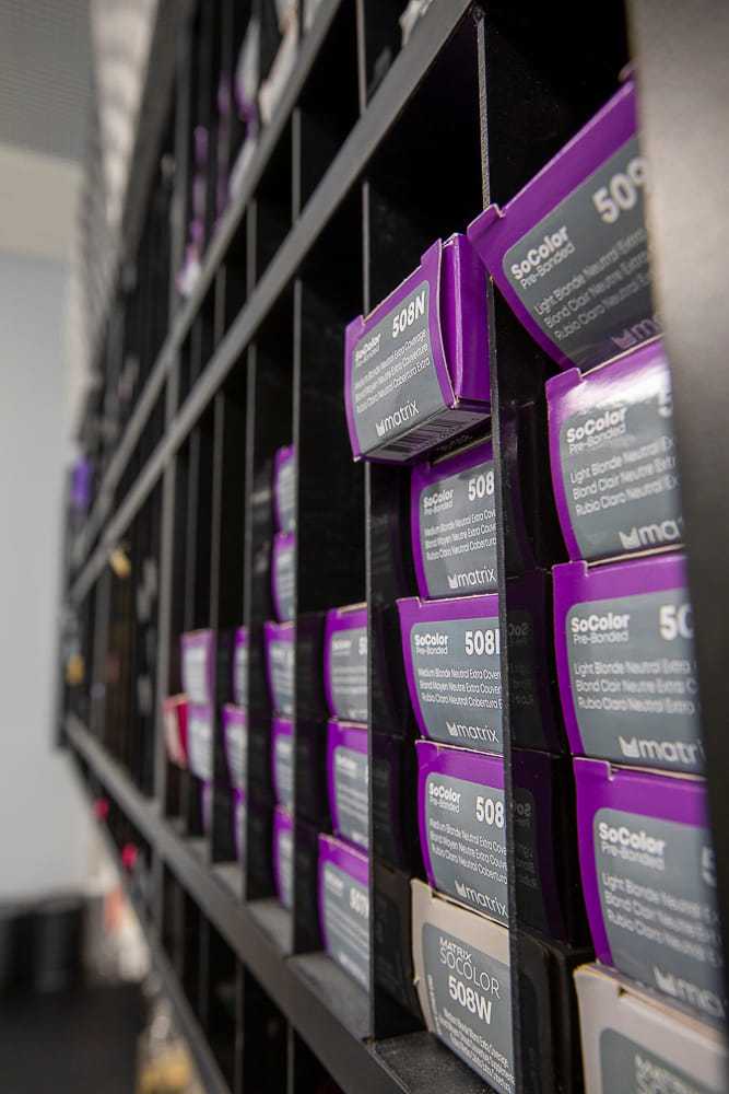 Shelves of boxed hair dye products in a salon or store setting.