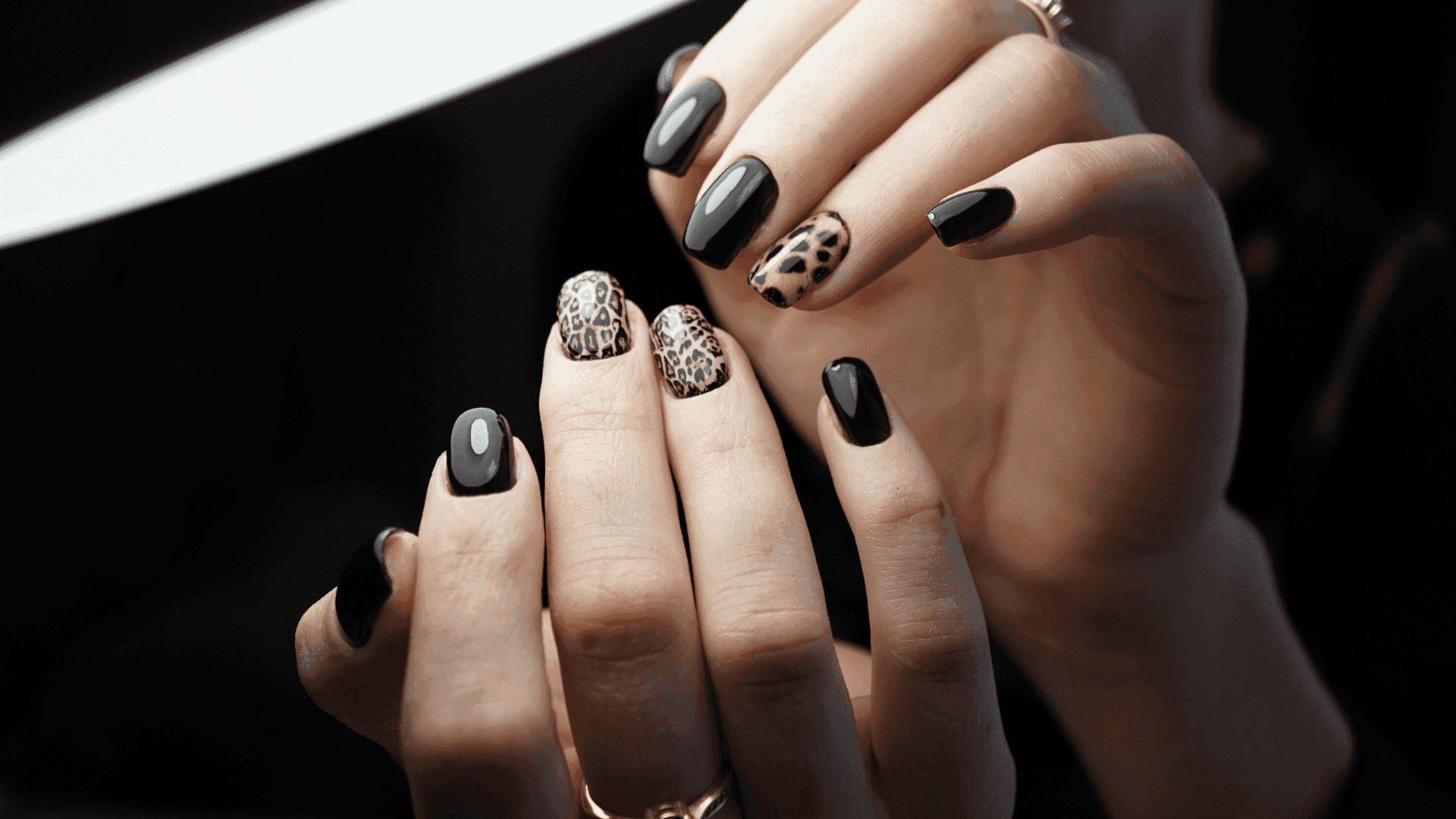 Nail art with black polish and animal print designs on fingertips.
